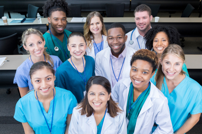 A group of doctors in scrubs, smiling and standing together